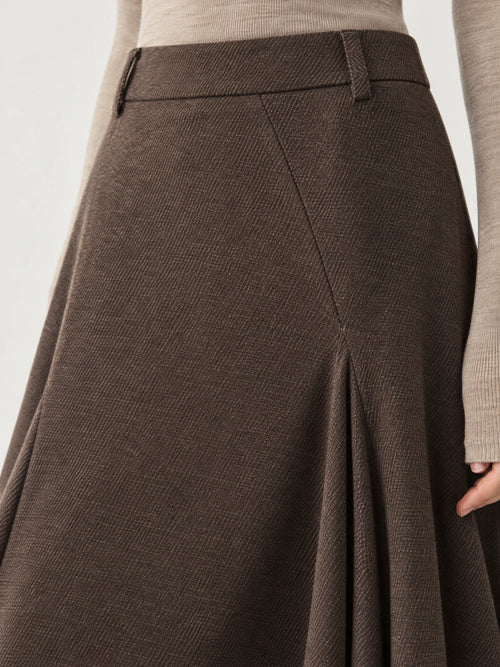 Close-up of the Brown asymmetric hem midi skirt showing the waistband, belt loops, diagonal texture, and layered front panel.