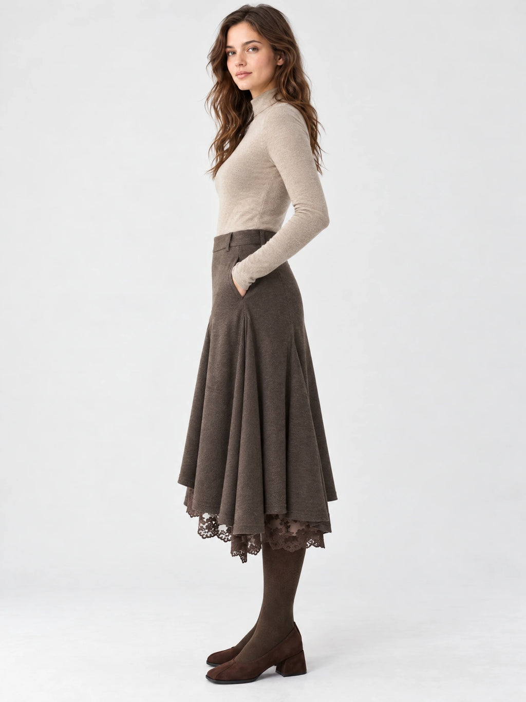 Side studio view of a model wearing a Brown asymmetric hem midi skirt with a flared silhouette, lace-trimmed hem, and hand in pocket.