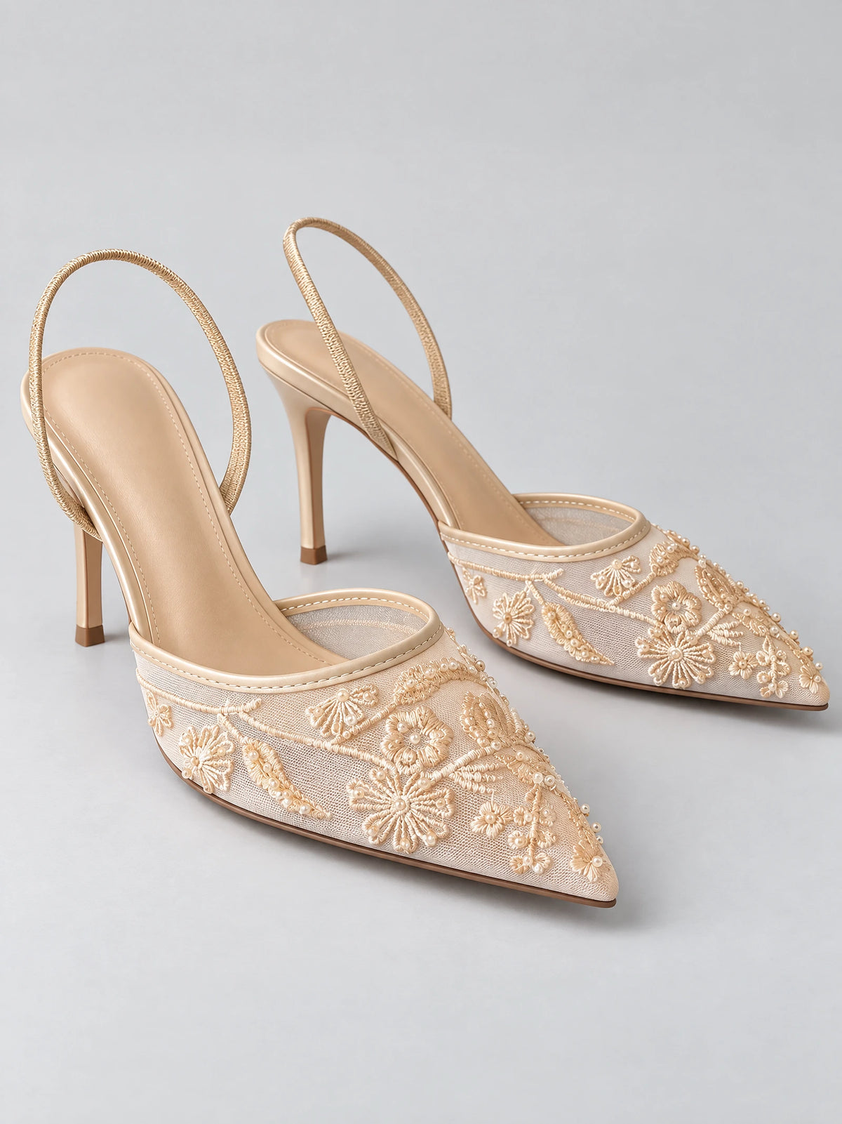 Beige back strap slingback high heels with pointed toes, embroidered floral mesh uppers, and slim stiletto heels.