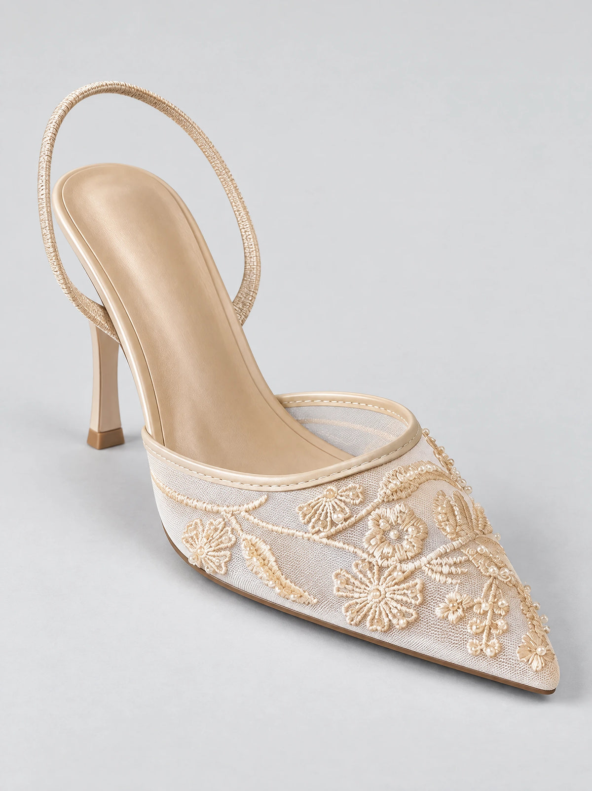 Three-quarter view of a Beige slingback high heel with a pointed toe, embroidered floral mesh upper, bead details, and slim heel.