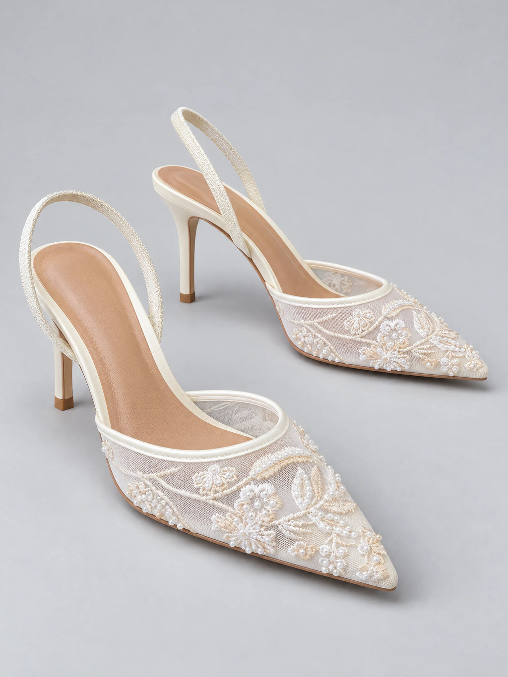 White back strap slingback high heels with pointed mesh toes, embroidered floral appliqués, and beaded detailing shown in a studio product photo.