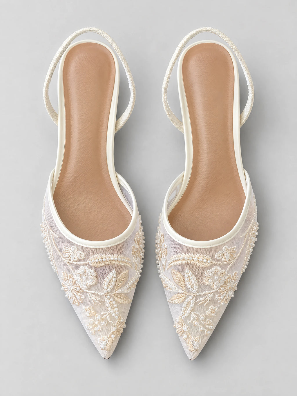 Top-down view of White back strap slingback high heels with pointed toes, embroidered floral mesh, and beaded embellishments.