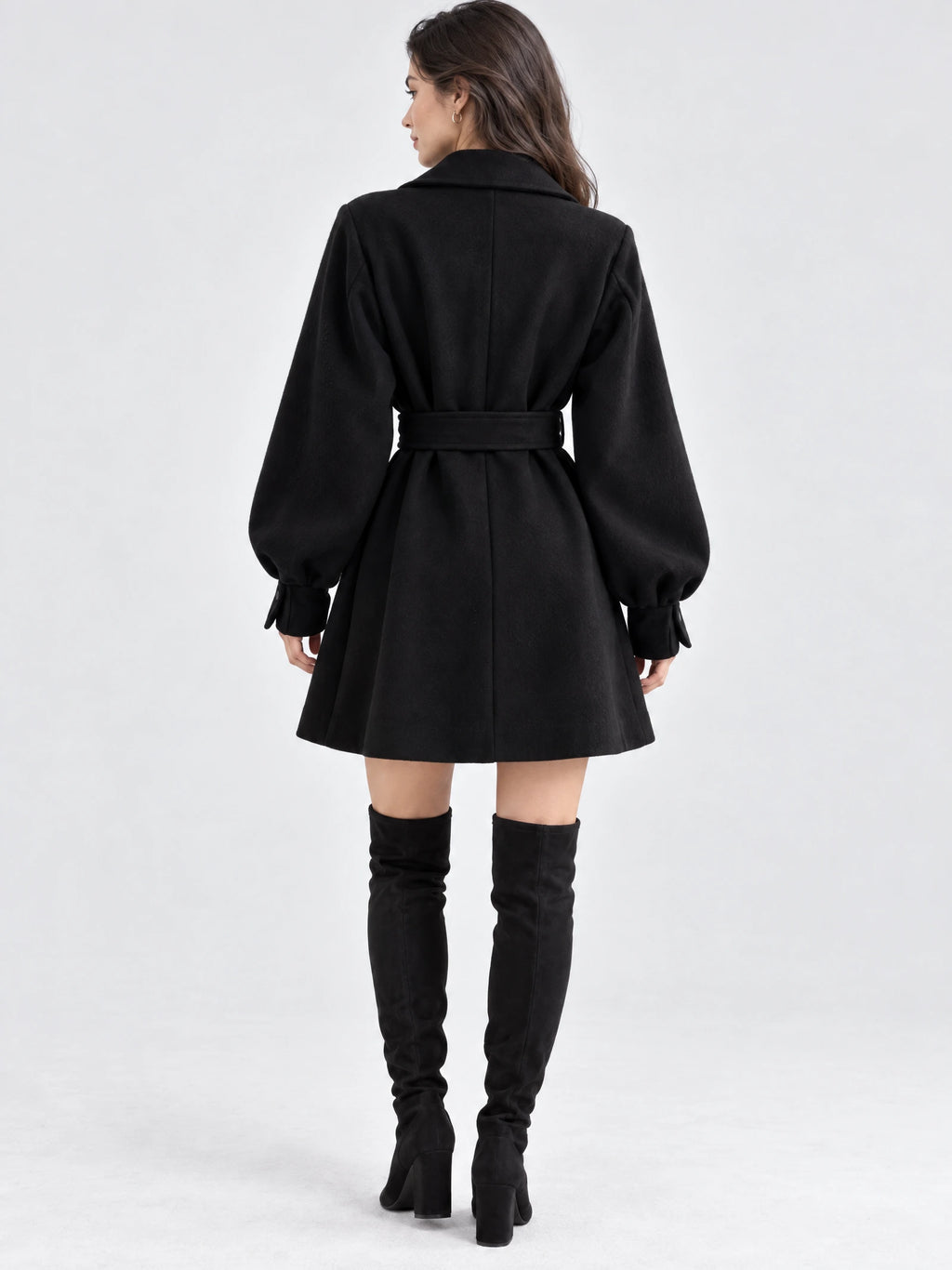 Rear studio view of a model wearing a Black belted lantern sleeve wool coat with a flared skirt and center back seam.