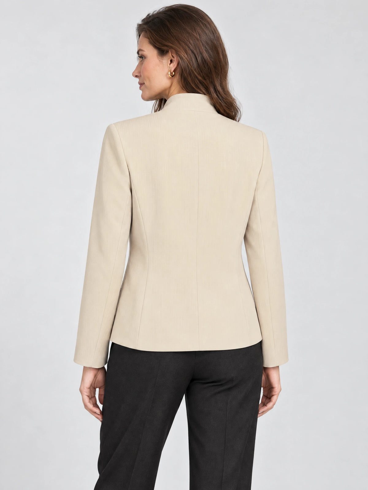 Rear view of a model wearing a Beige Blazer Blouse with long sleeves, a high collar, and tailored back seams.