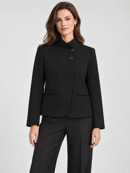 Front studio view of a model wearing a Black Blazer Blouse with an asymmetric high collar, button closure, and welt pockets.