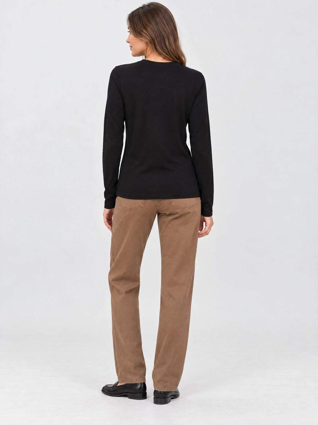Back view of a model wearing a Black cotton long sleeve T-shirt with a crew neckline in a studio.