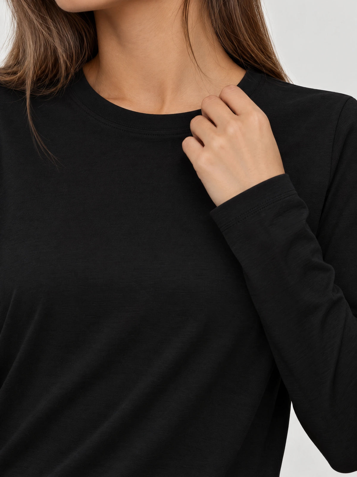 Close-up of a Black cotton long sleeve T-shirt showing the stitched crew neckline and cuff detail.