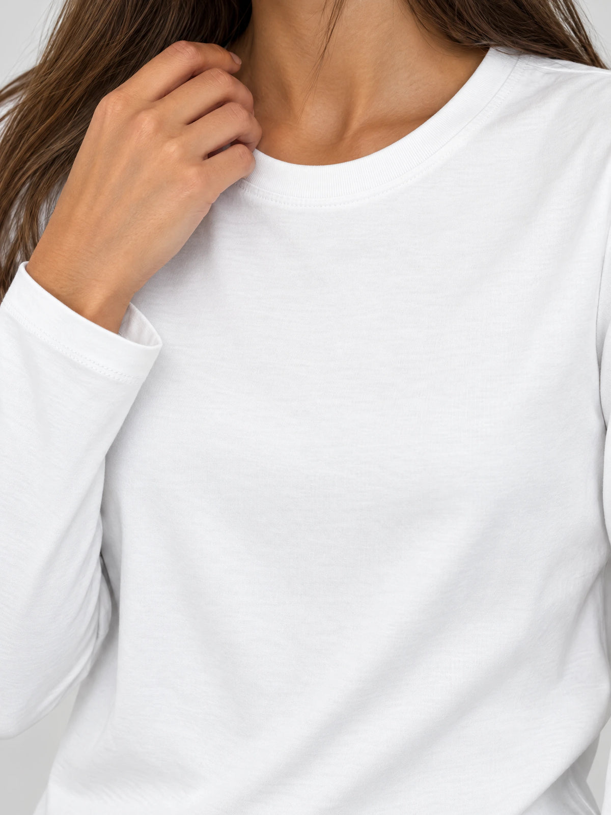 Close-up of a White cotton long sleeve T-shirt showing the ribbed O-neck, smooth fabric, and stitched cuff.