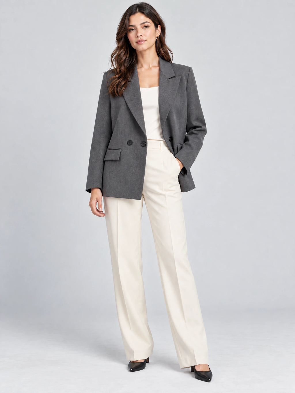 Front studio view of a model wearing a Gray double breasted blazer with notched lapels and flap pockets.