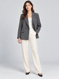 Front studio view of a model wearing a Gray double breasted blazer with notched lapels and flap pockets.