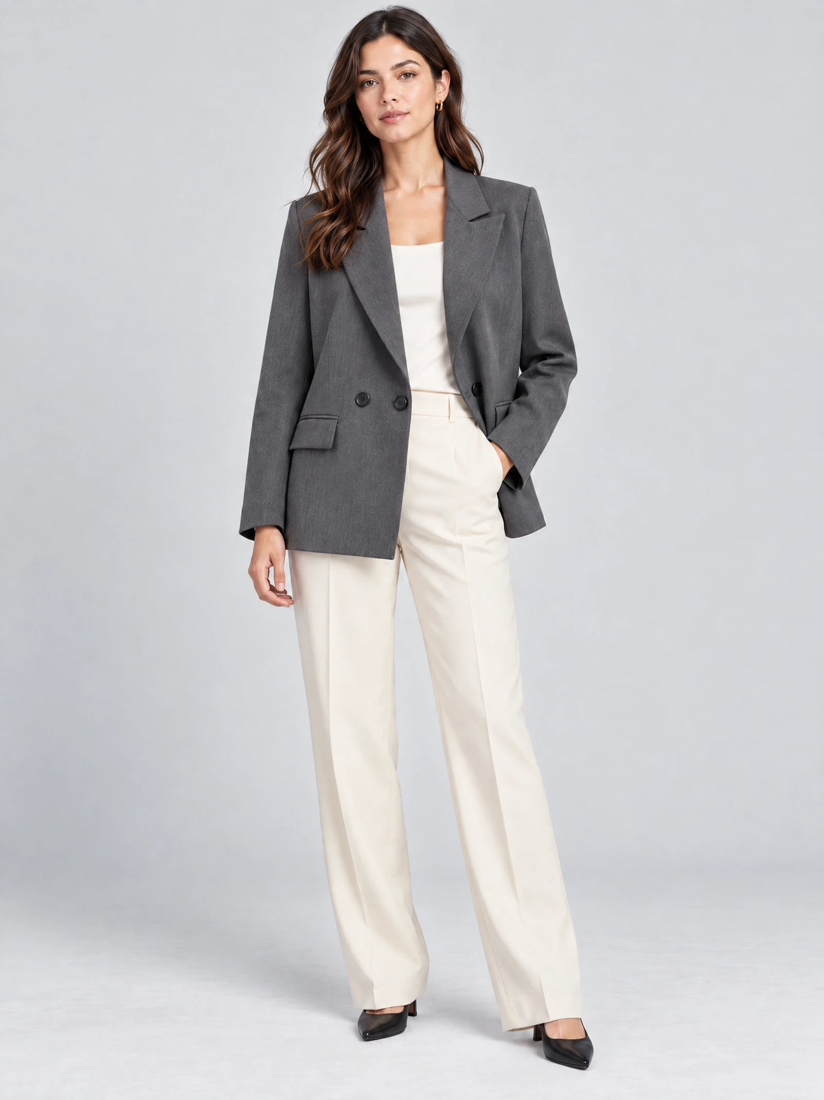Front studio view of a model wearing a Gray double breasted blazer with notched lapels and flap pockets.