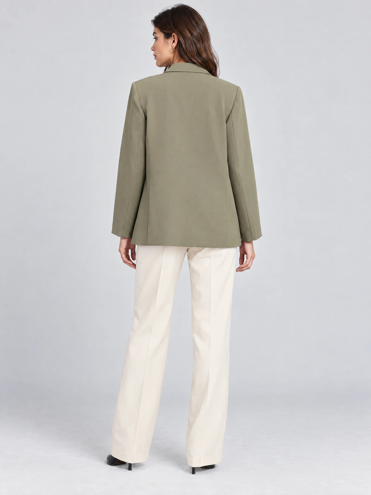 Back view of a model wearing a Green double breasted blazer with a straight, hip-length silhouette.