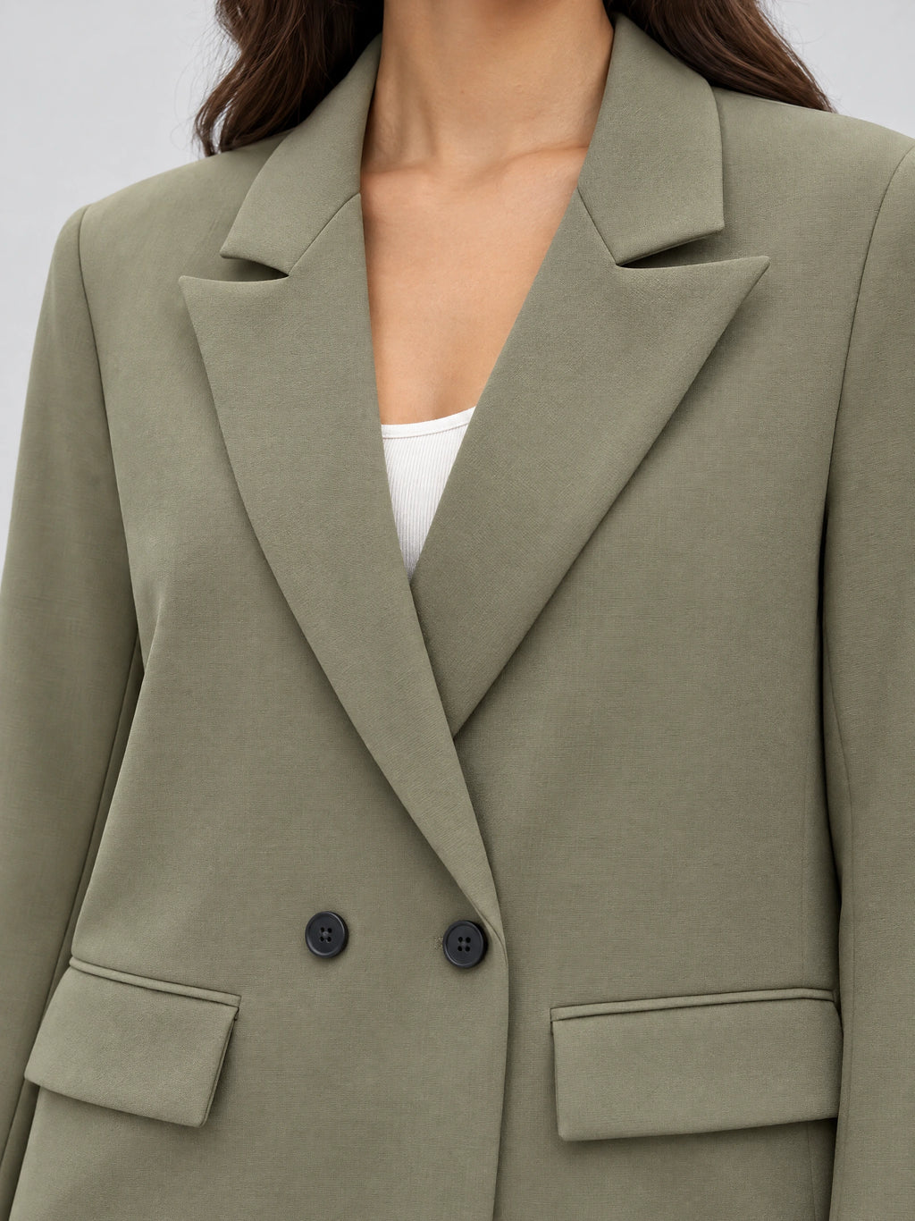 Close-up of a Green double breasted blazer with notched lapels, dark buttons, and flap pockets.