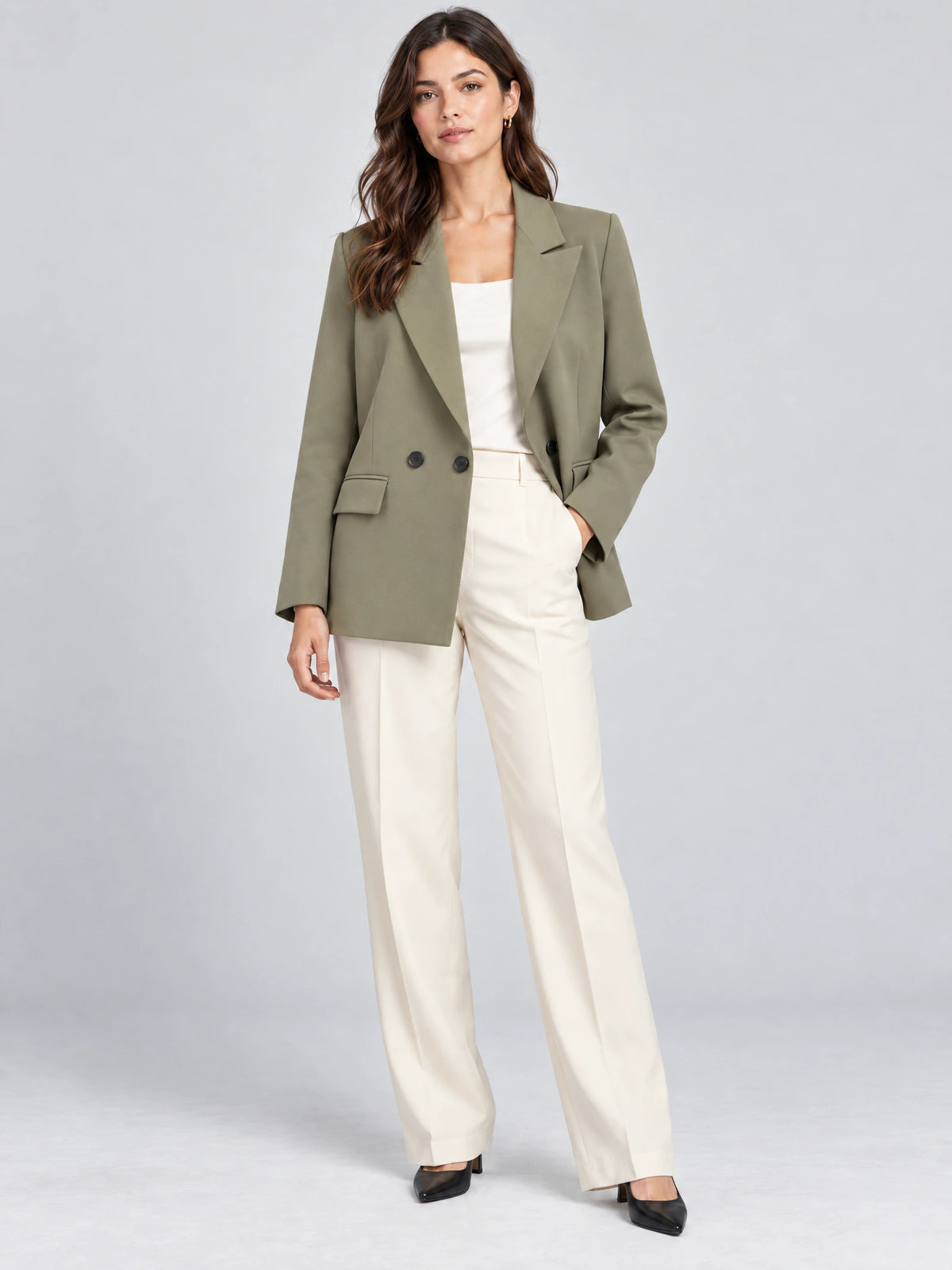 Front studio view of a model wearing a Green double breasted blazer with notched lapels and flap pockets.