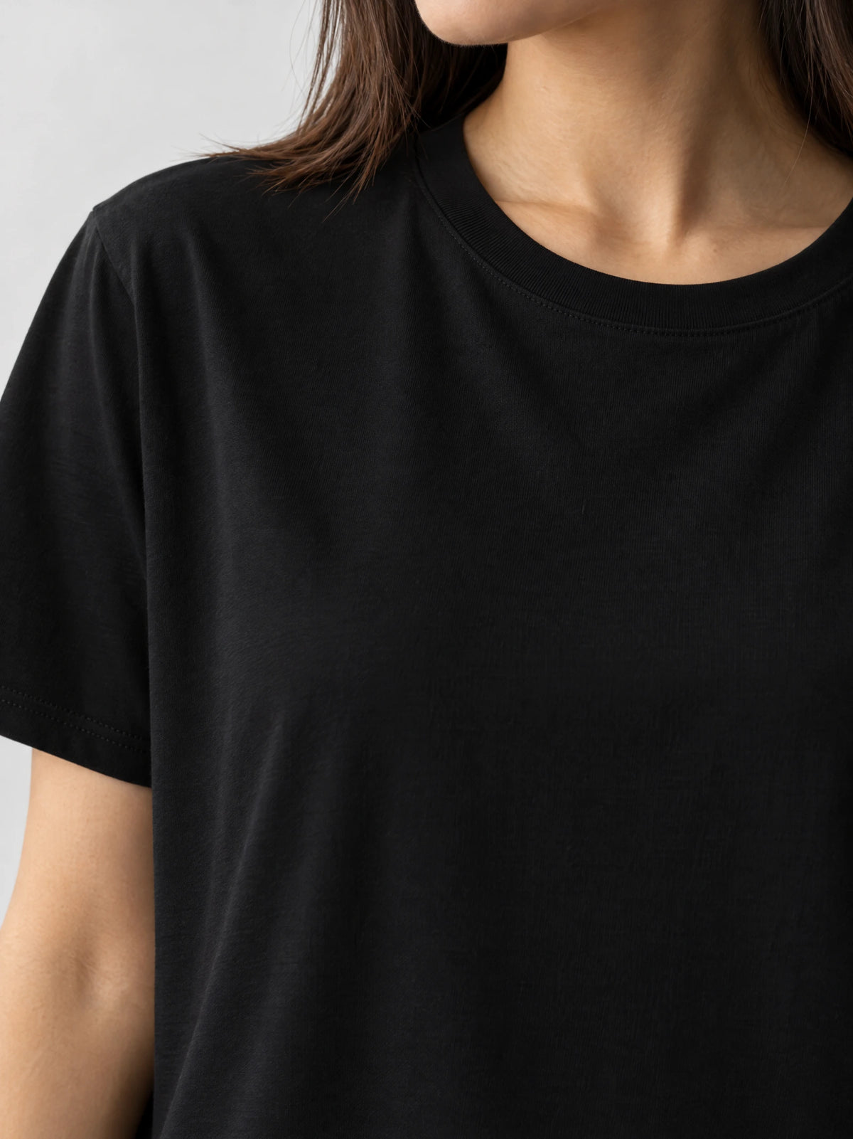 Close-up of a Black women’s cotton T-shirt showing the ribbed crew neckline, shoulder seam, and short sleeve.