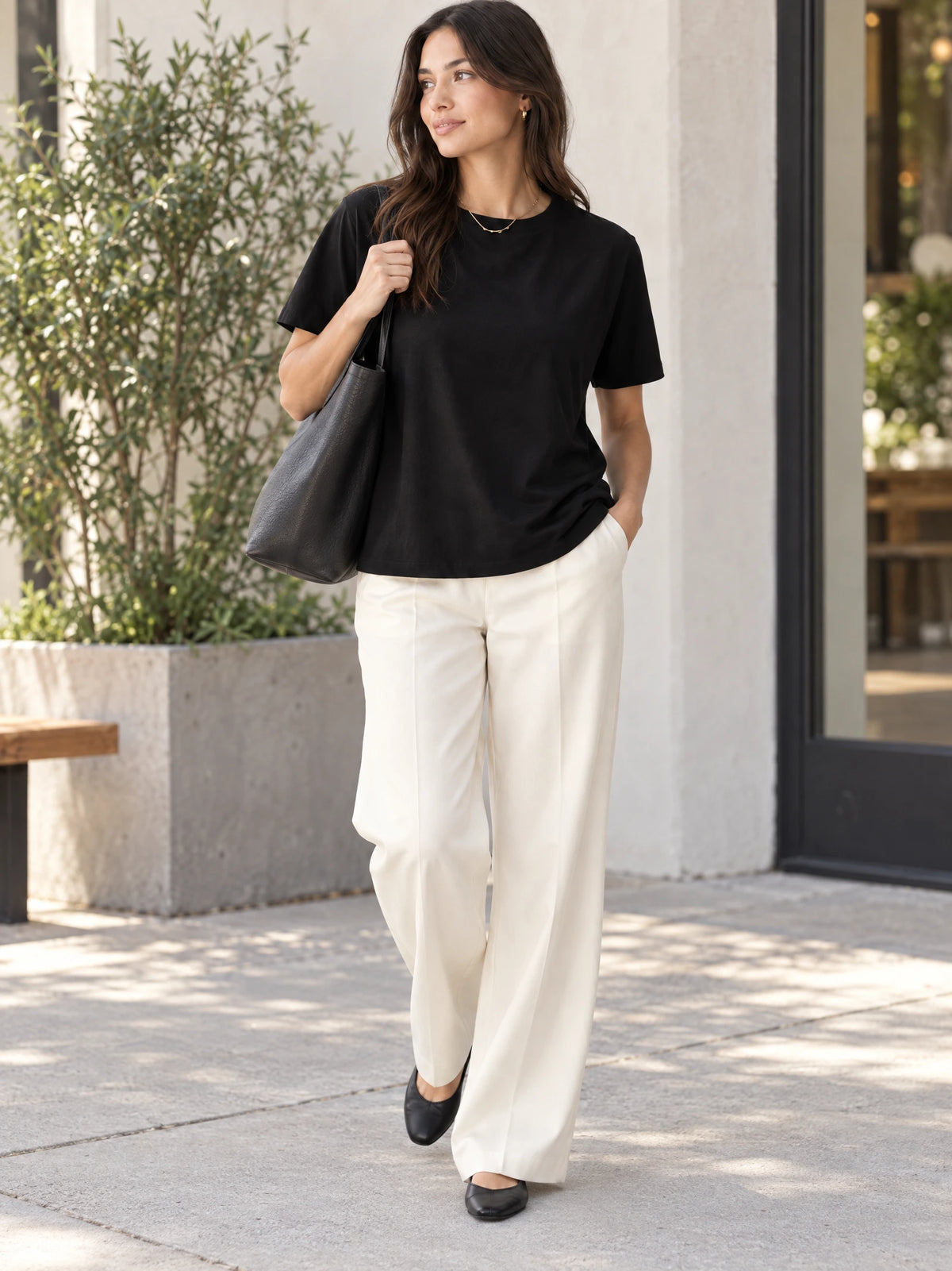 Model wearing a Black heavyweight cotton T-shirt while walking outdoors with a shoulder bag.