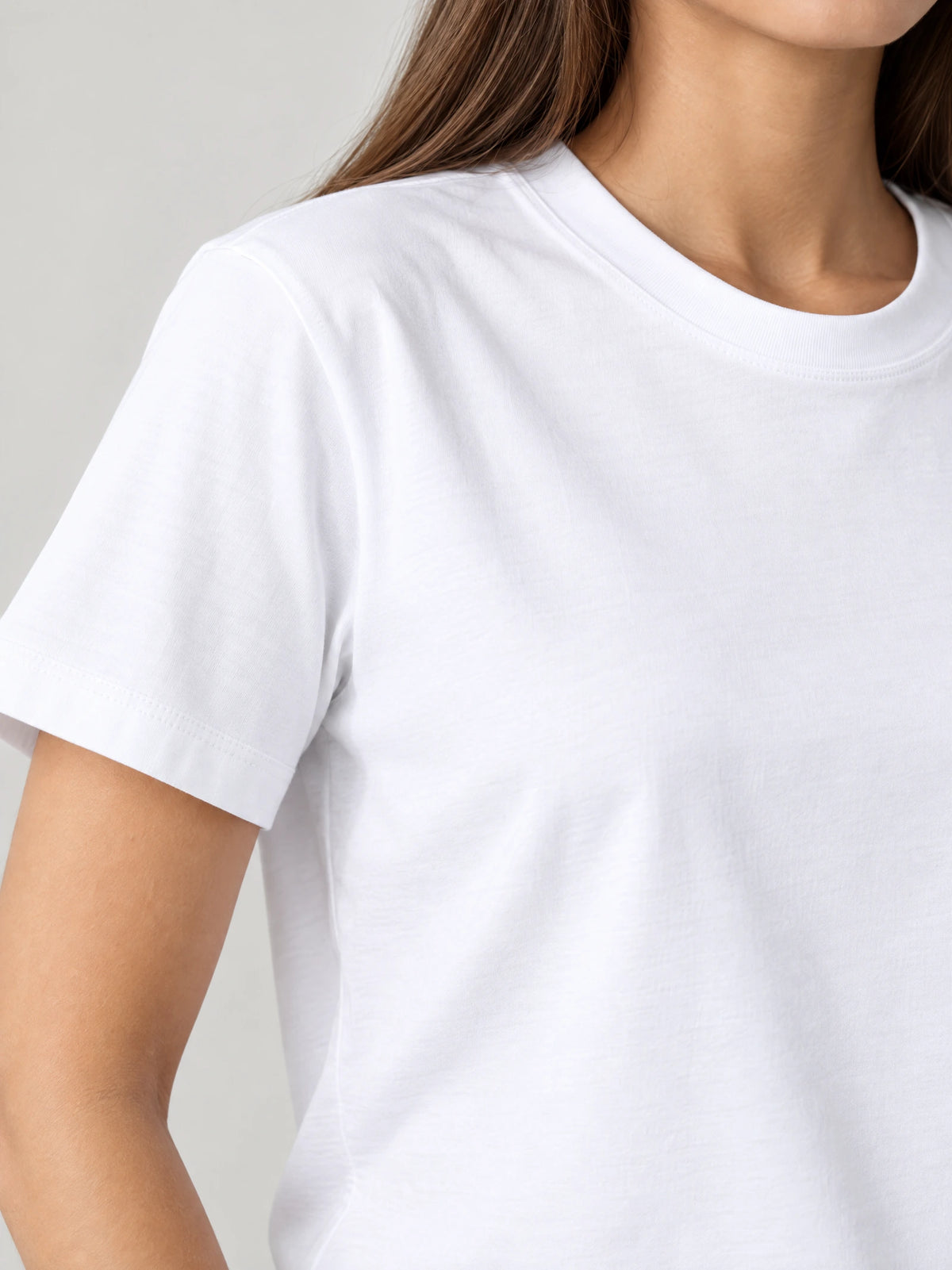 Close-up of a White women's heavyweight cotton T-shirt showing the ribbed crew neckline, shoulder seam, and short sleeve hem.