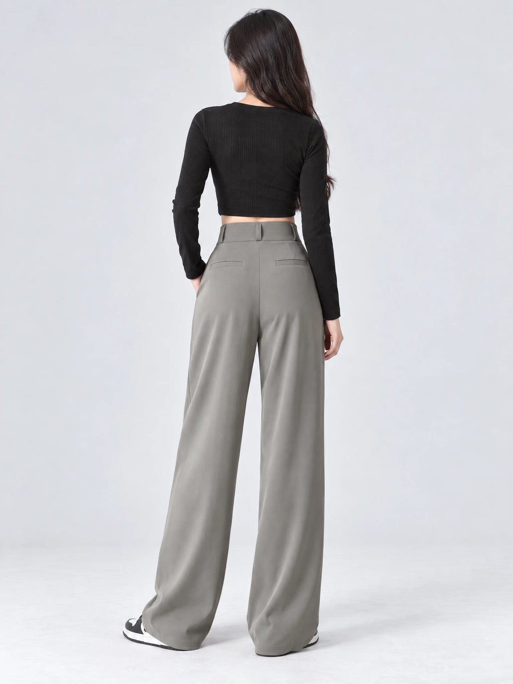 Rear studio view of a model wearing Gray high waist wide leg pants with back welt pockets and a wide waistband.