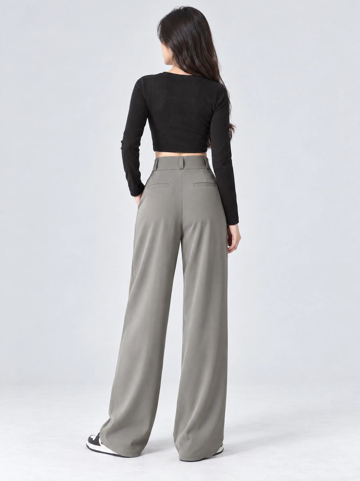 Rear studio view of a model wearing Gray high waist wide leg pants with back welt pockets and a wide waistband.