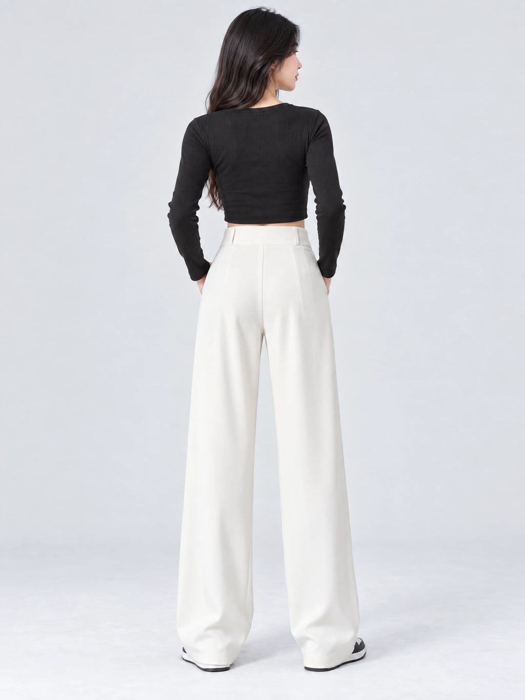 Rear studio view of a model wearing White high waist wide leg pants with a smooth waistband and flowing full-length legs.