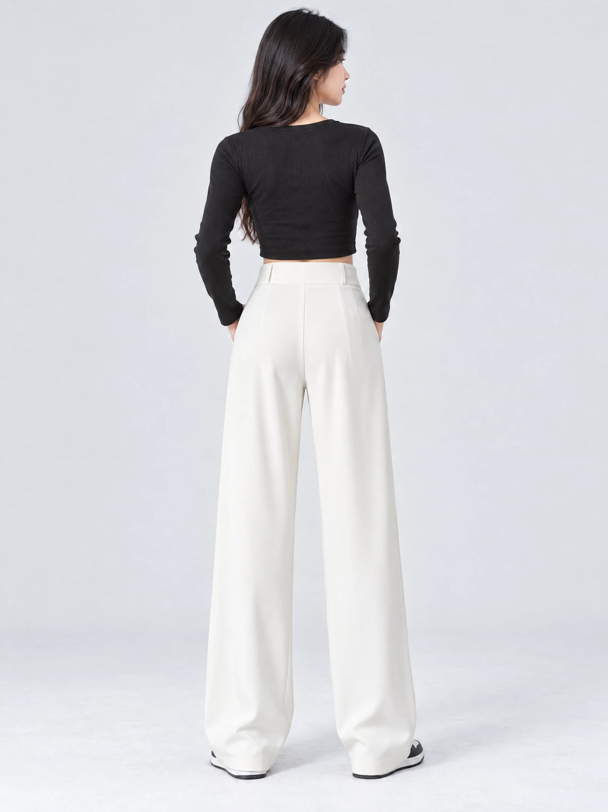 Rear studio view of a model wearing White high waist wide leg pants with a smooth waistband and flowing full-length legs.