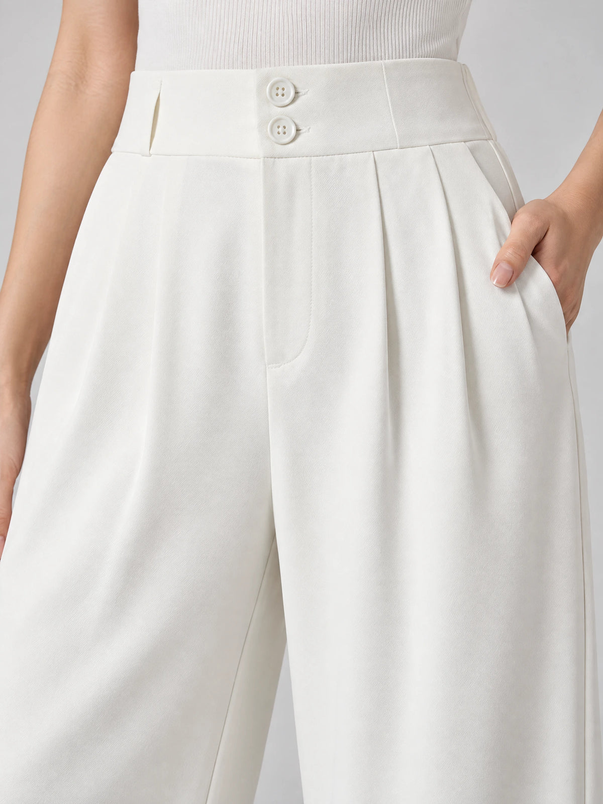 Close-up of White high waist wide leg pants with a two-button waistband, front pleats, and a side pocket.
