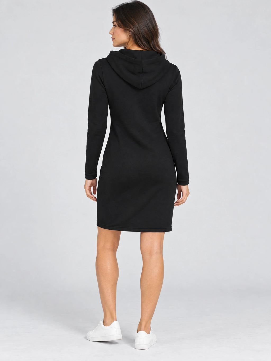 Rear studio view of a model wearing a Black cotton hooded dress with long sleeves and a knee-length hem.