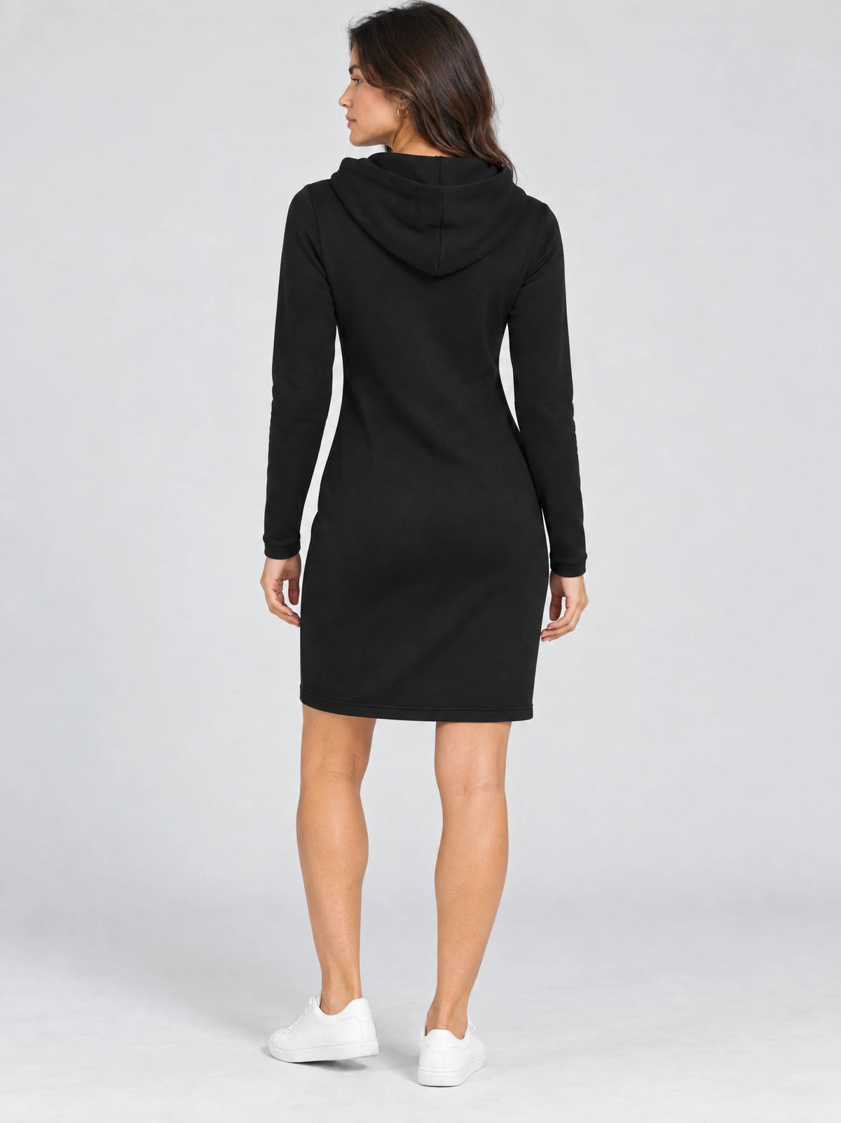 Rear studio view of a model wearing a Black cotton hooded dress with long sleeves and a knee-length hem.