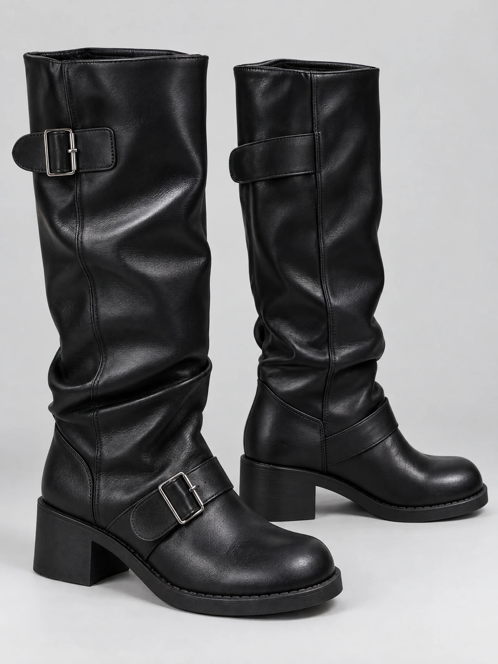 Black leather knee-high chunky boots shown in a studio pair view with buckled straps, rounded toes, and block heels.