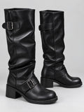 Black leather knee-high chunky boots shown in a studio pair view with buckled straps, rounded toes, and block heels.