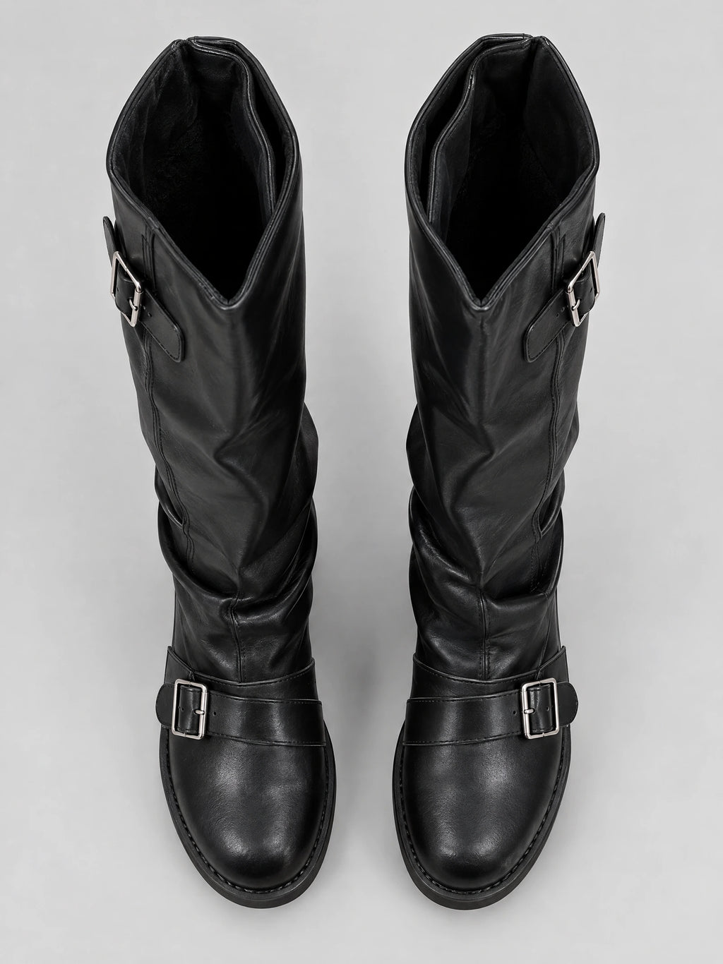 Top-down view of Black leather knee high chunky boots with buckled straps across the instep and upper shaft.