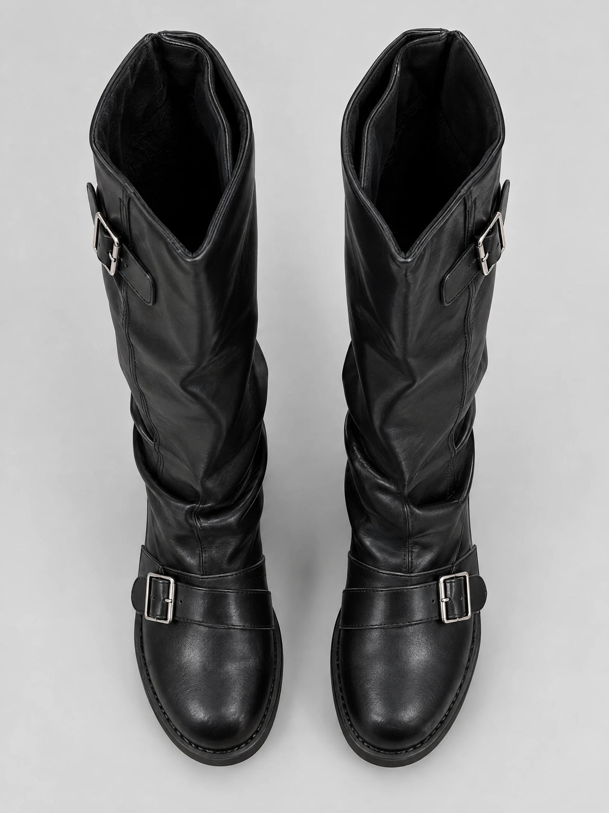 Top-down view of Black leather knee high chunky boots with buckled straps across the instep and upper shaft.