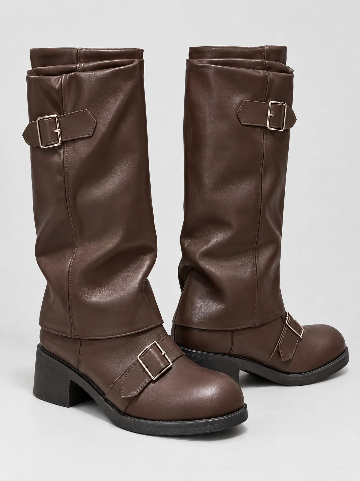 Brown leather knee-high chunky boots with buckle straps and block platform heels, shown in a studio product view.