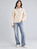 Front studio view of a model wearing a Beige knit full zip sweater with a ribbed stand collar and cuffs.