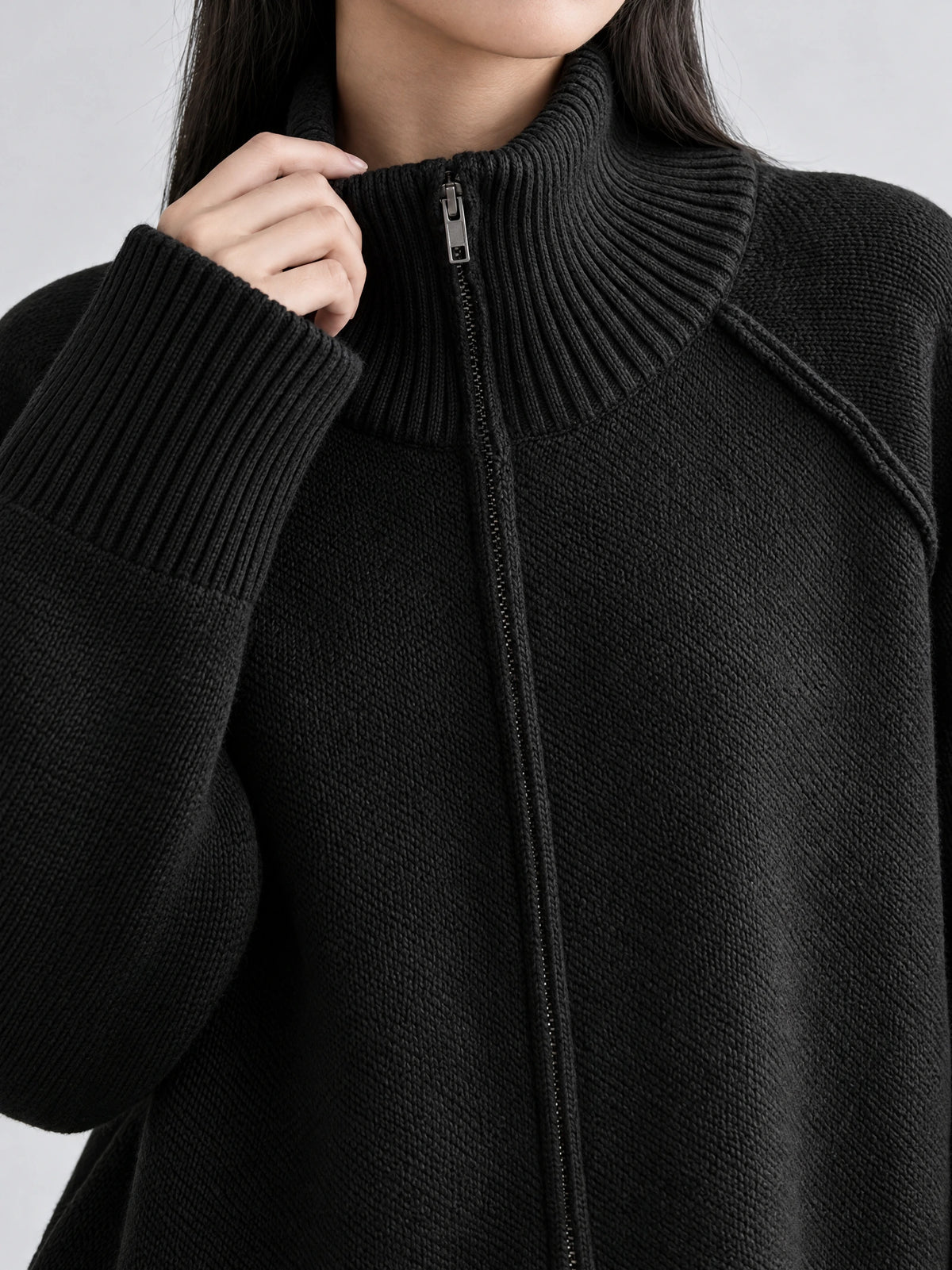 Close-up of a Black Knit Full Zip Sweater showing the ribbed high collar, front zipper, and textured knit.