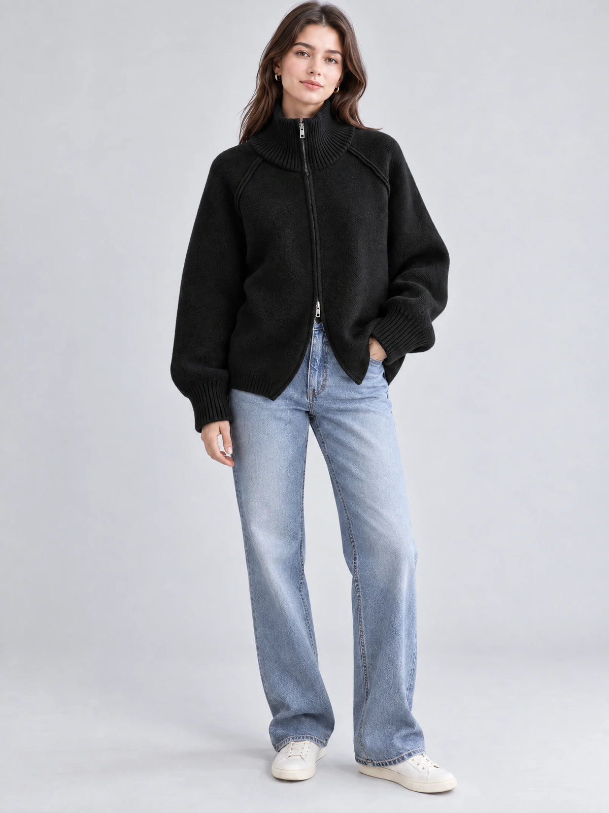 Model wearing a Black knit full zip sweater with a ribbed high collar and cuffs in a front studio view.