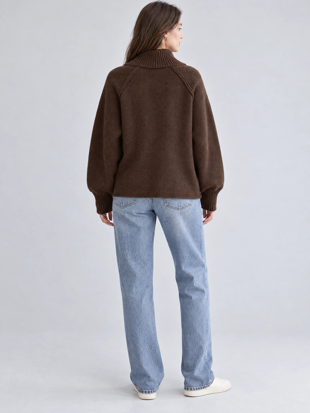 Back view of a model wearing a Brown knit full zip sweater with a ribbed high collar, raglan seams, and ribbed cuffs.