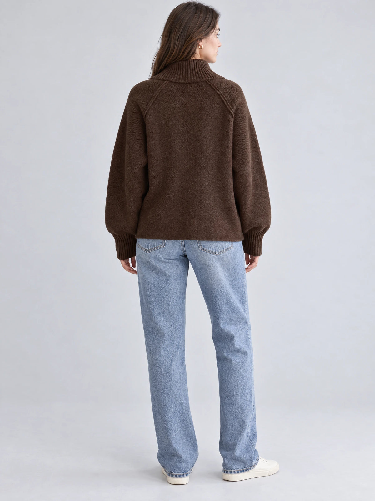 Back view of a model wearing a Brown knit full zip sweater with a ribbed high collar, raglan seams, and ribbed cuffs.