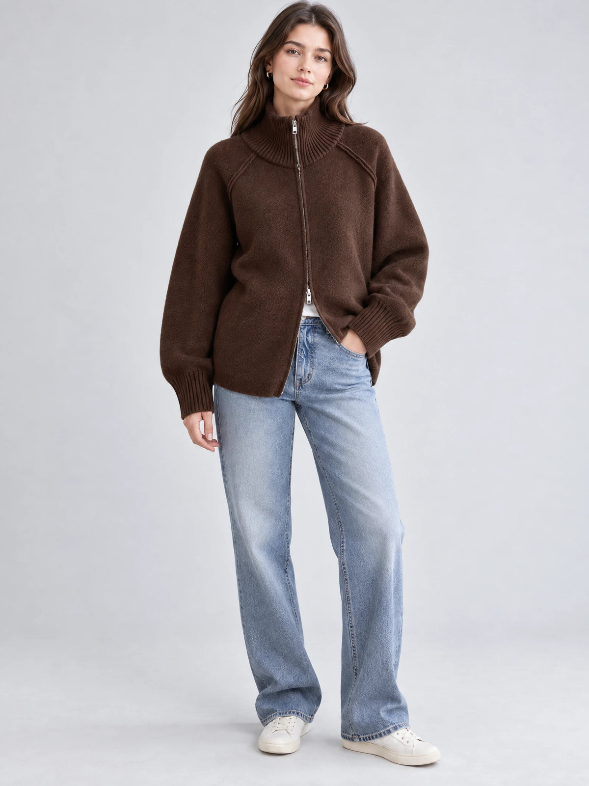 Model wearing a Brown knit full zip sweater with a ribbed high collar and cuffs in a front studio view.