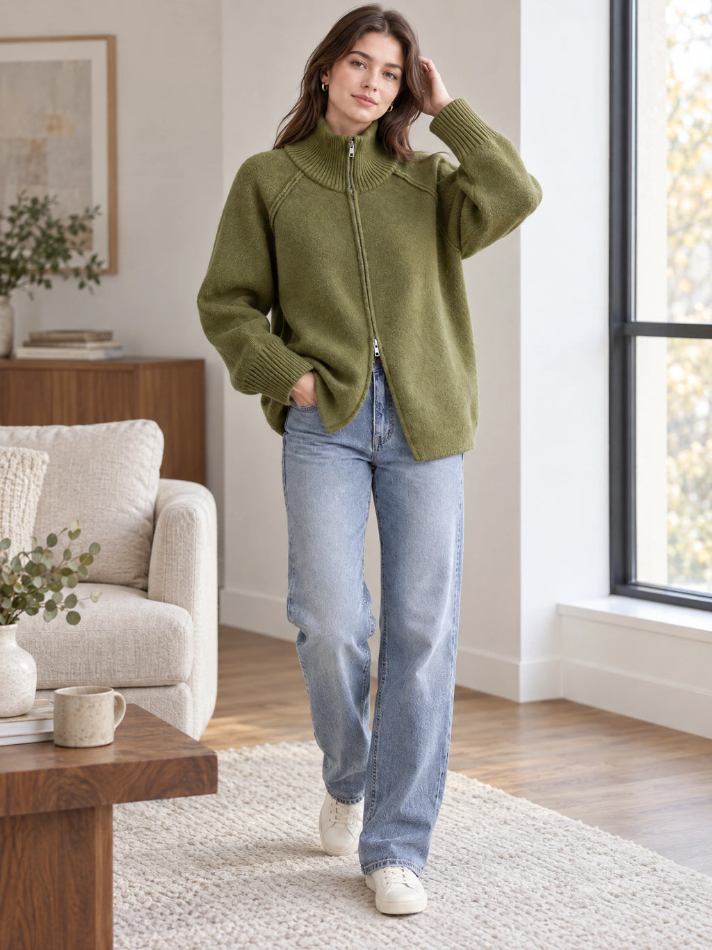 Model wearing a Green knit full zip sweater with a ribbed high collar in a bright living room.