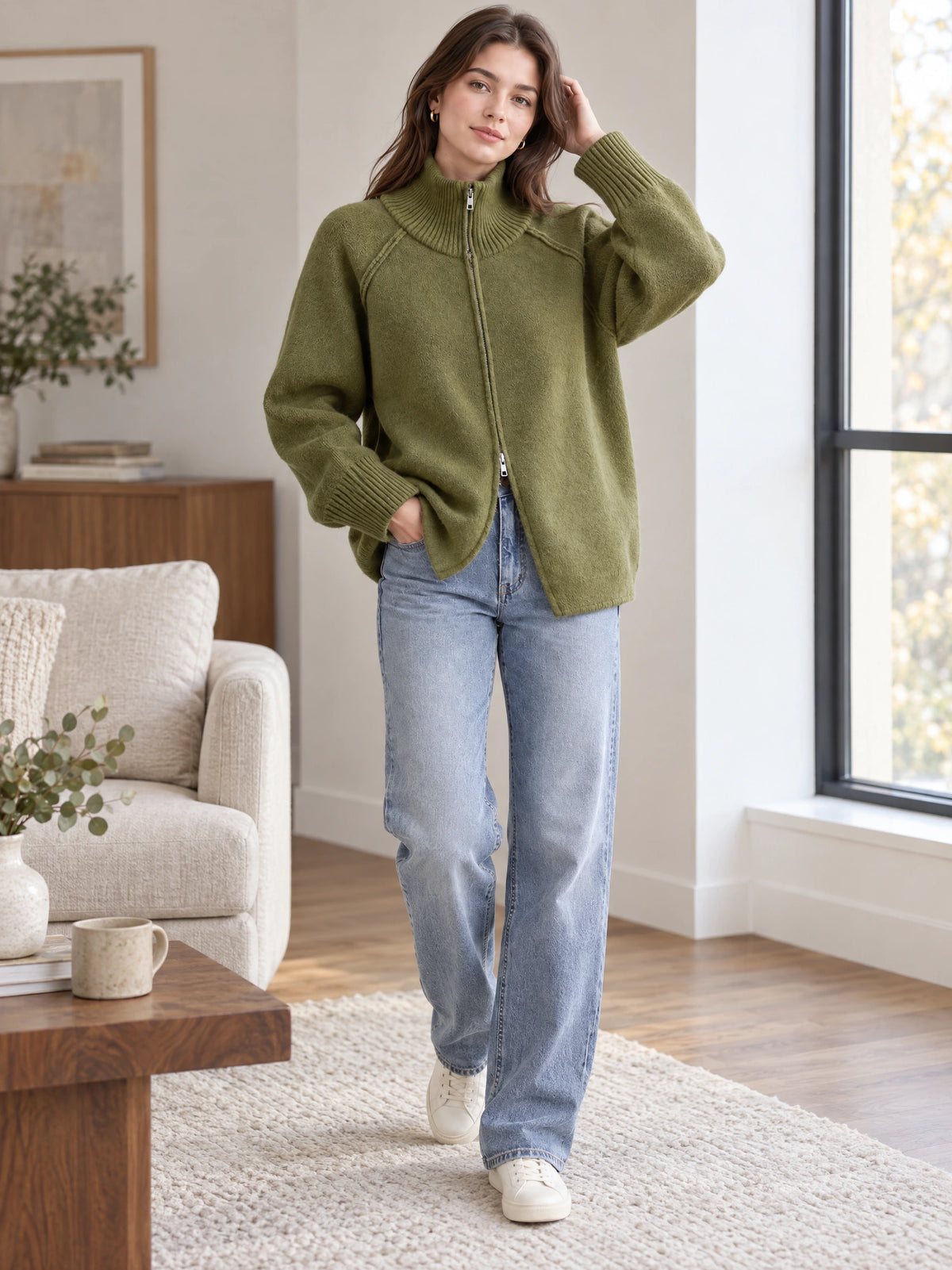 Model wearing a Green knit full zip sweater with a ribbed high collar in a bright living room.