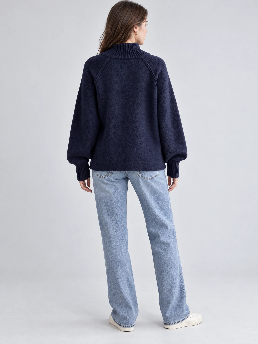 Rear studio view of a model wearing the Navy Knit Full Zip Sweater with a ribbed high collar, raglan sleeves, and ribbed cuffs.