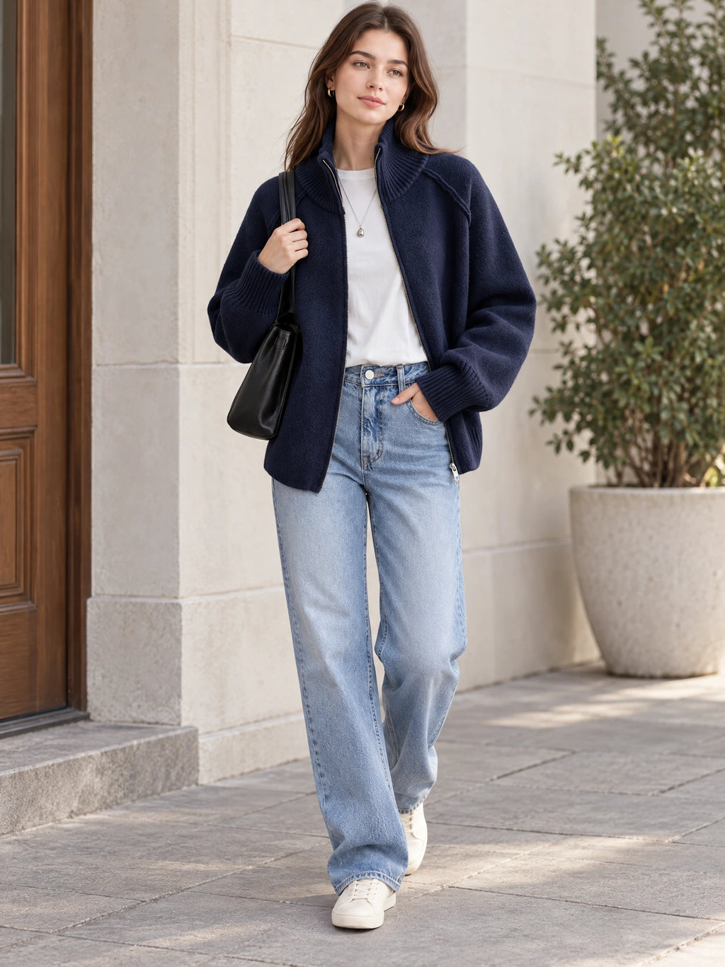 Model walking outdoors in a Navy knit full zip sweater with a ribbed stand collar and cuffs.