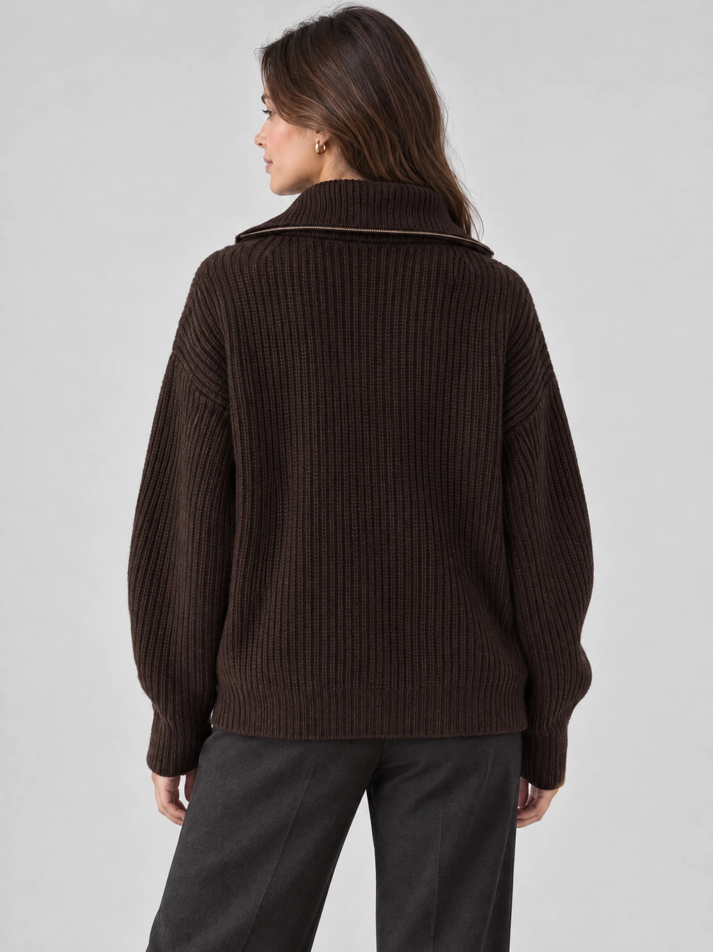 Rear view of a model wearing a Brown ribbed knit turtle neck cardigan with a wide zip-trimmed collar.
