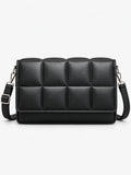 Black leather cross body bag shown from the front in a studio, with a padded grid panel and adjustable strap.