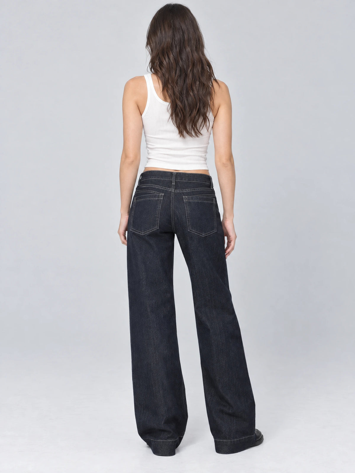 Rear studio view of a model wearing Blue Lowe Rise Jeans with wide legs and back patch pockets.