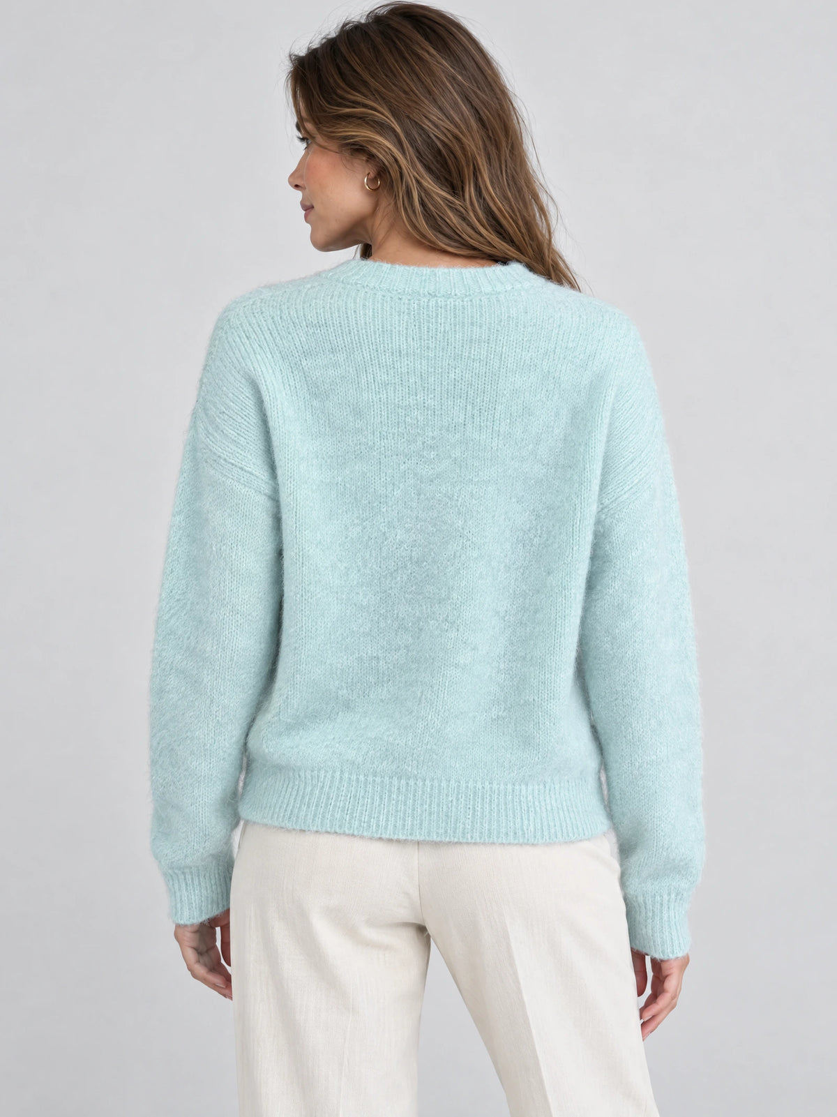 Back view of a model wearing a Light Blue women’s mohair winter sweater with a fuzzy knit texture and ribbed trim.