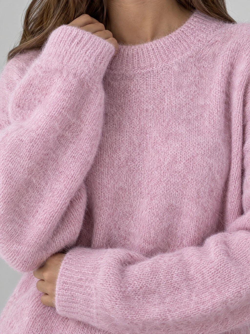 Close-up of a Pink women’s mohair winter sweater showing its fuzzy knit texture, ribbed crew neckline, and wide ribbed cuffs.