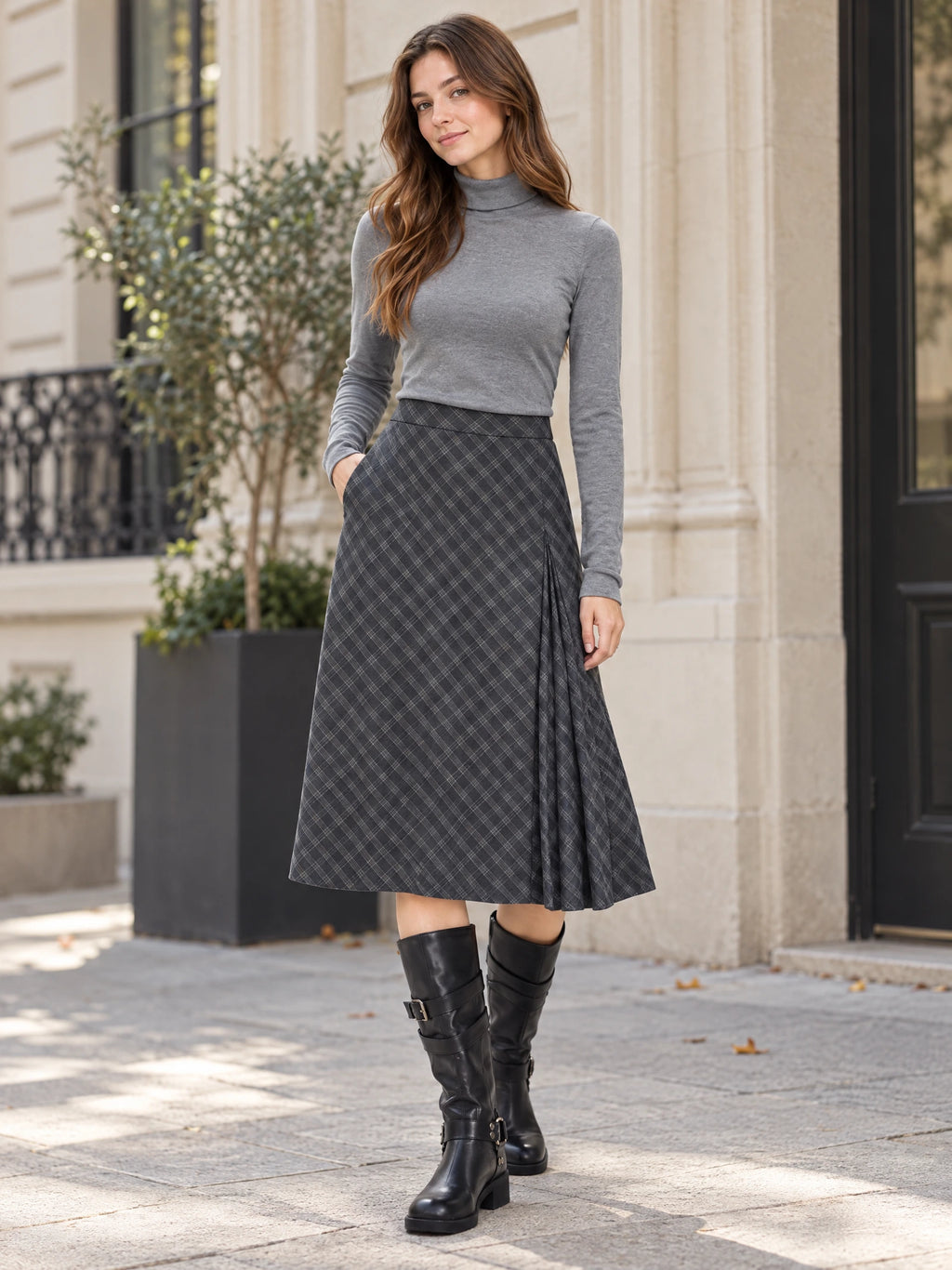 Model wearing a Gray checkered Pleated A-line Skirt with a pleated side panel while standing outside a building.