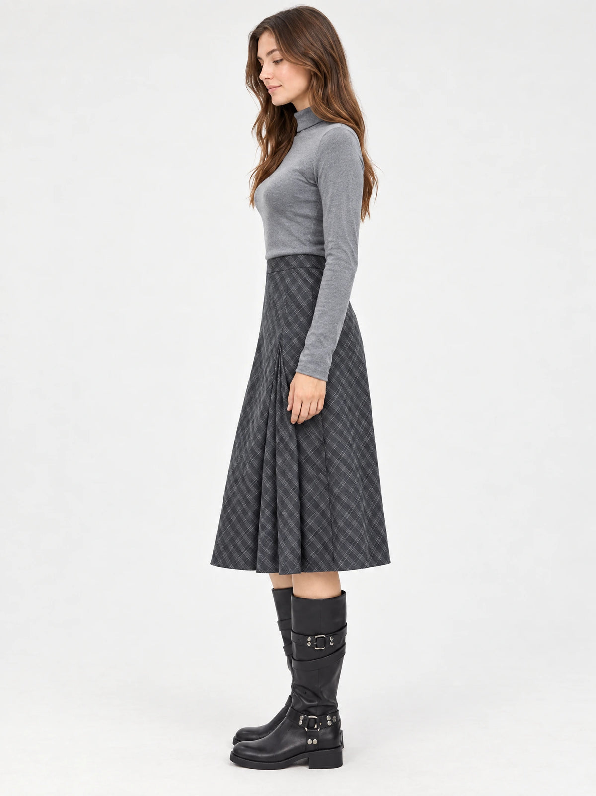 Side studio view of a model wearing a Gray pleated A-line midi skirt with a check pattern and flared silhouette.